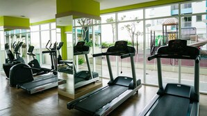 A gym with treadmills, ellipticals, and a mirrored wall. - Relax Studio Apartment At The Nest Near Puri By Travelio (Tangerang)