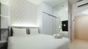 A hotel room with a large bed, a wardrobe, a mirror, and a door.