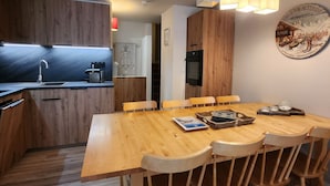 A modern kitchen with wooden cabinets, a built-in oven, and a dining area with a wooden table and chairs. - Renovated triplex apt for 7 in Avoriaz, terrace, ski locker (Avoriaz)