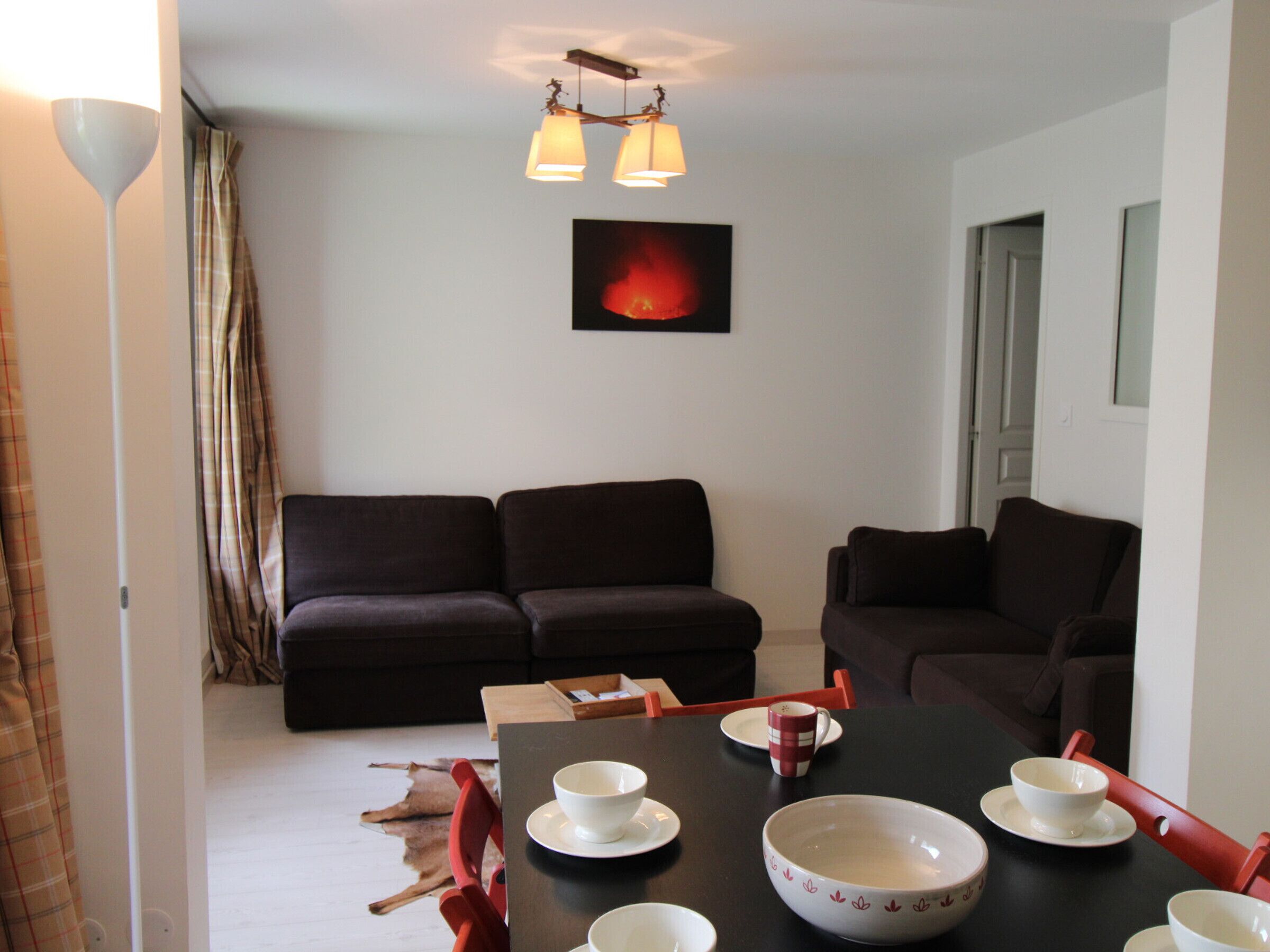 Un coin repas avec une table dressée pour quatre personnes, deux canapés et un luminaire fixé au mur.