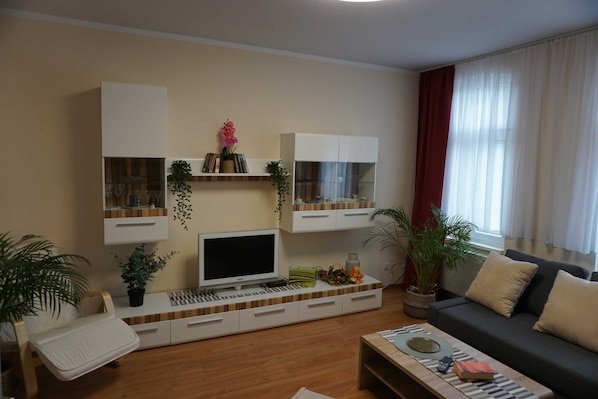 Una sala de estar moderna con un televisor de pantalla plana, estanterías empotradas, un sofá y una mesa de centro.