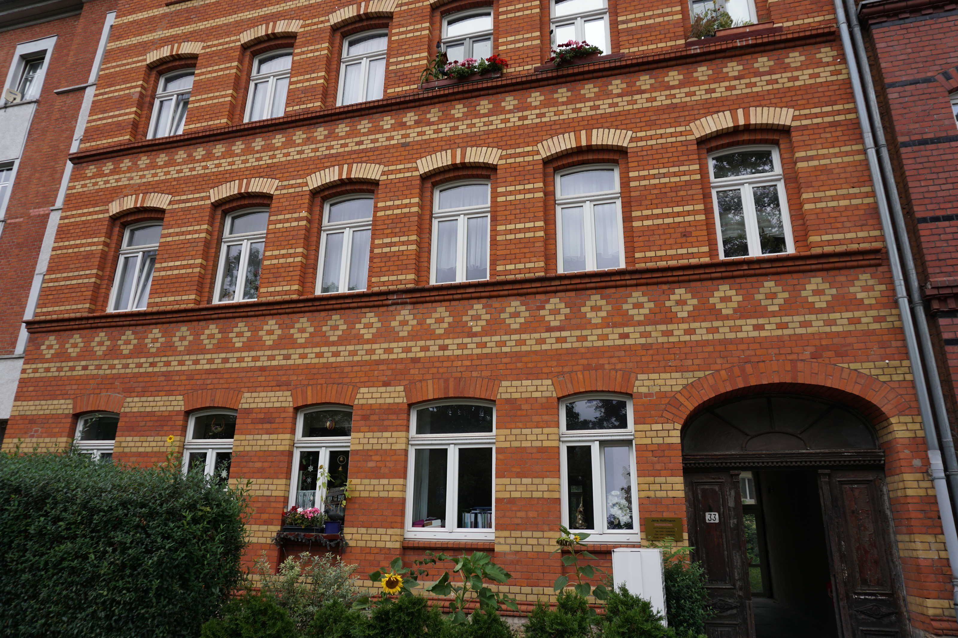 Ein roter Backsteinbau mit mehreren Fenstern und einer Tür.