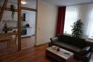 A living room with a sofa, a coffee table, and a view of a kitchen. - Poldi 3 - Apartments Poldi (Erfurt)