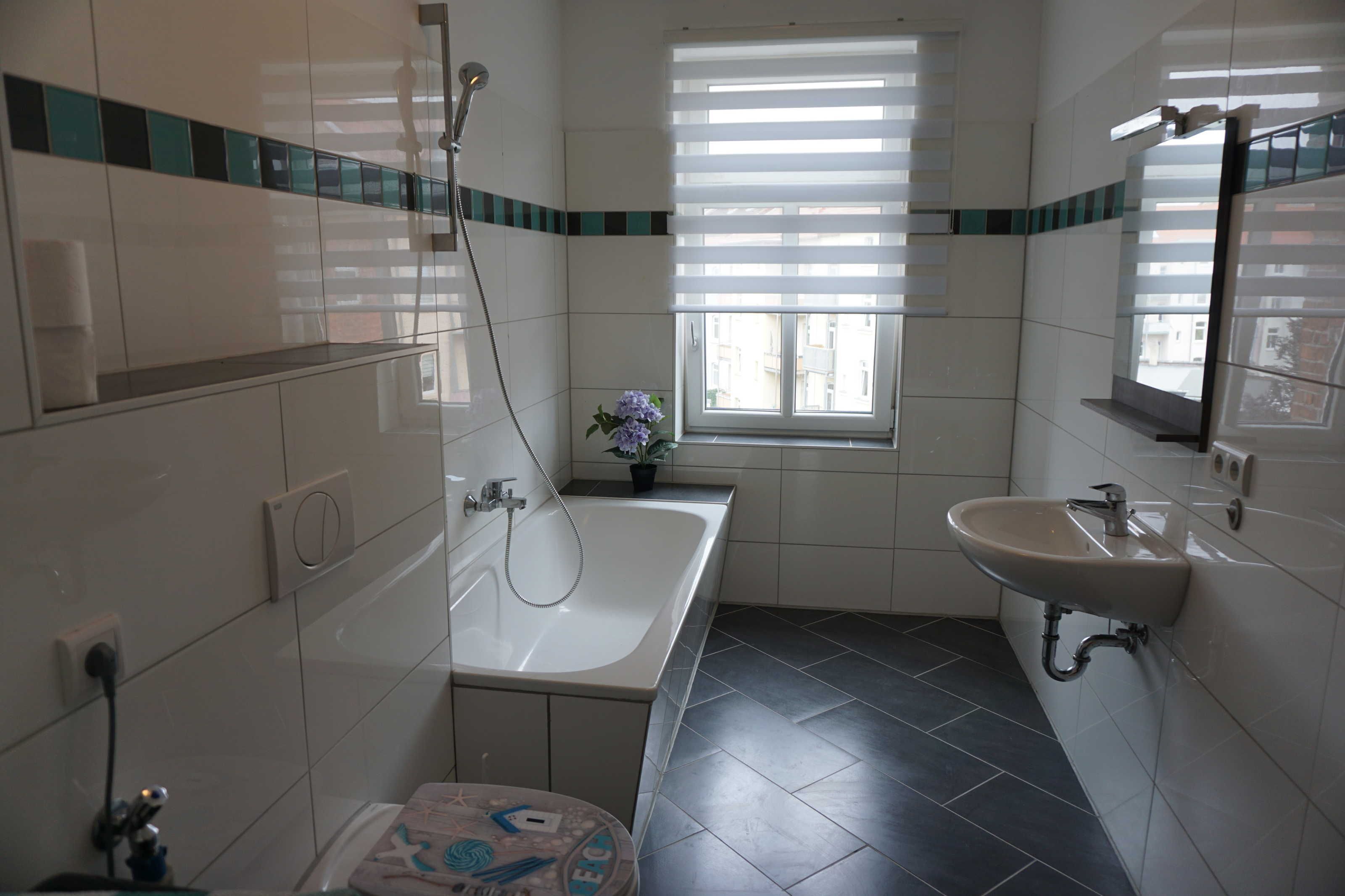 Ein Badezimmer mit einer Badewanne, einem Waschbecken und einem Fenster mit Jalousien.