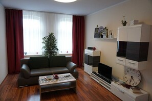 A living room with a sofa, coffee table, TV, and a clock on the wall. - Poldi 3 - Apartments Poldi (Erfurt)