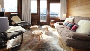 Une pièce chaleureuse avec un décor intérieur en bois, un canapé, un fauteuil, une petite table et une lampe.