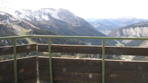 Une vue sur la montagne depuis un balcon doté d’une balustrade en bois.