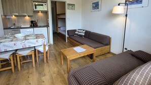 Un espacio habitable compacto con kitchenette, comedor, sofá y cama.