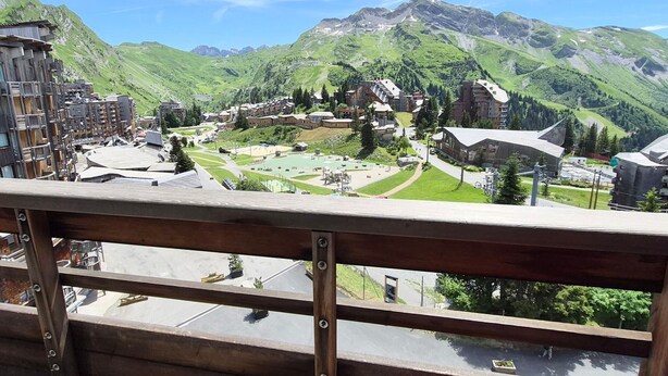 Un pueblo de montaña con edificios tradicionales, una plaza central y vistas de las colinas circundantes.