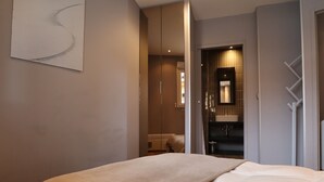 A modern hotel room with a large bed, a bathroom with a mirror and sink, and a hallway leading to another room. - Avoriaz: Wellness space, 8 pers, 90 sqm (Avoriaz)