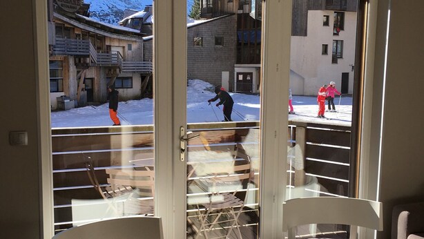 A hotel room with a sliding glass door leading to a snowy outdoor area with people skiing. - Avoriaz: Wellness space, 8 pers, 90 sqm (Avoriaz)