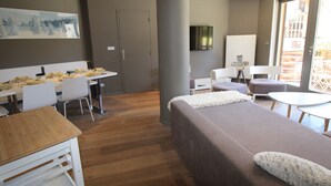 A modern hotel room with a large bed, a desk with chairs, a television, and a balcony with outdoor seating. - Avoriaz: Wellness space, 8 pers, 90 sqm (Avoriaz)