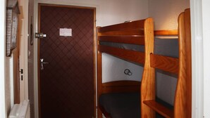 A narrow hallway with a wooden bunk bed and a door with a lock.
