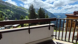 A balcony with a metal railing overlooking a mountainous landscape with trees and a clear sky. - Avoriaz: Renovated apartment for 5 guests with WIFI (Avoriaz)