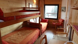 A wooden cabin with bunk beds, a single bed, a chair, a table, and a window with a view. - Avoriaz: Renovated apartment for 5 guests with WIFI (Avoriaz)