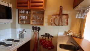 A compact kitchen with a microwave, stove, and sink. There are wooden cabinets above the stove and a hanging rack with kitchen utensils. - Avoriaz: Renovated apartment for 5 guests with WIFI (Avoriaz)