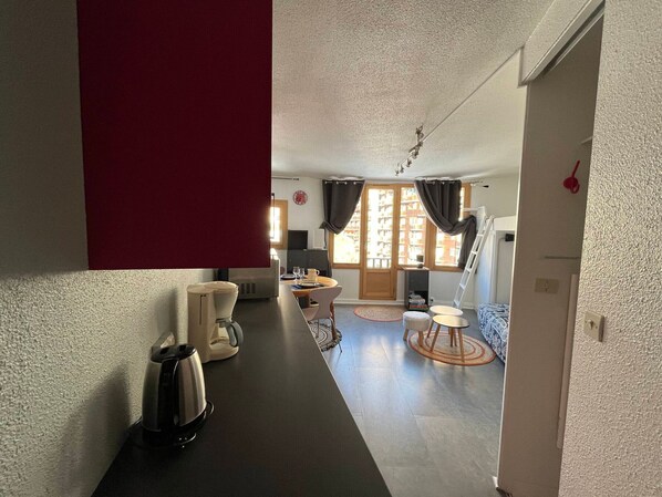 Cozy living space with a kitchenette, dining area, and bedroom featuring a bed and wardrobe.