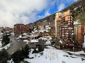Une ville enneigée, avec des immeubles à plusieurs étages, dont une pharmacie et un restaurant.