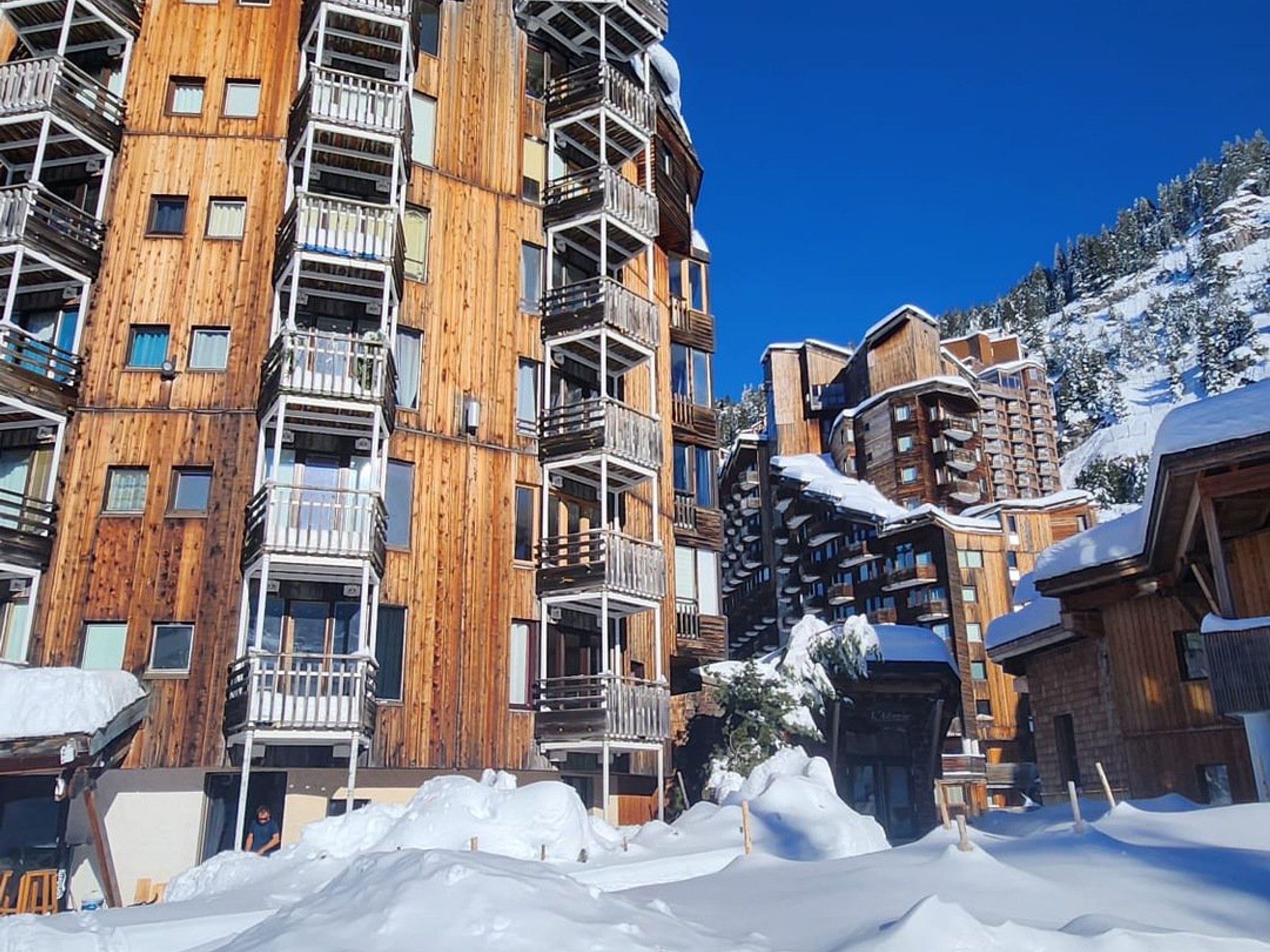 A multi-story wooden building with balconies, surrounded by snow.