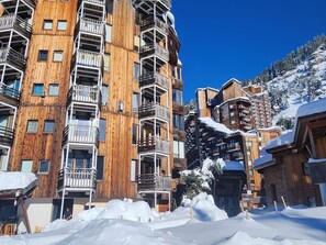 A multi-story wooden building with balconies, surrounded by snow.