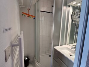 Bathroom features a shower area with a glass door, a sink with a chrome faucet, and a mirror.