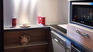A compact kitchen with a microwave, a dishwasher, and a small cabinet with decorative items. - Luxury studio 4 pers, ski-in/ski-out, fireplace, balcony, no pets, free wifi (Les Orres)