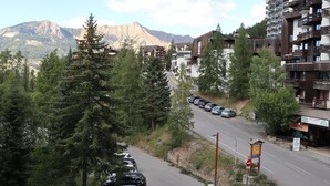 A mountain road with parked cars, a restaurant named "Pain Boucherie Aux Pizzas," and a building with balconies. - Luxury studio 4 pers, ski-in/ski-out, fireplace, balcony, no pets, free wifi (Les Orres)