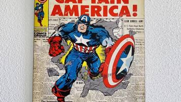 Capa de revista em quadrinhos do Capitão América, com um título grande, um personagem num traje azul e um escudo.