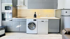 A compact kitchen with a washing machine, a microwave, and a refrigerator. - Romy Schneider (Vittel)