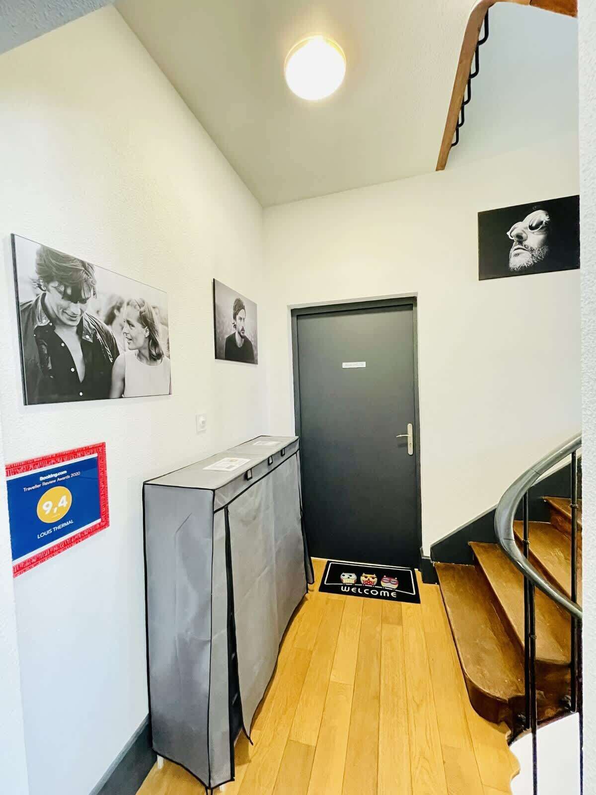 A hallway with a black door, a small desk, and a staircase.