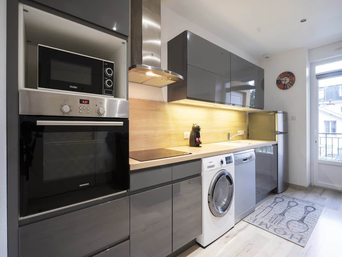 Eine moderne Küche mit Mikrowelle, Backofen, Waschmaschine und einem großen Fenster.