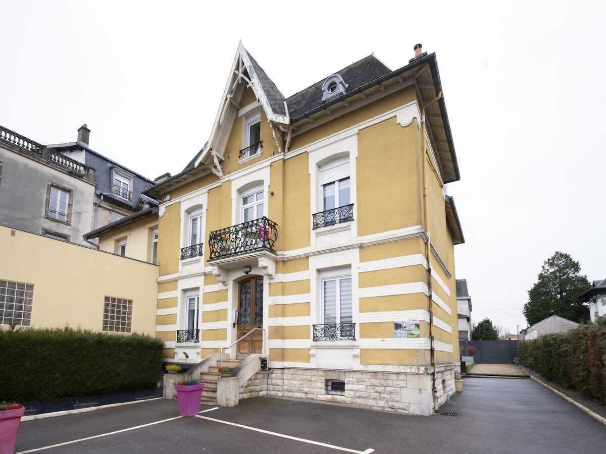 Een geel gebouw met een balkon, een trap en een deur.