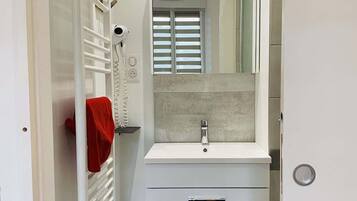 A bathroom with a white vanity, a mirror, a towel rack, and a radiator.