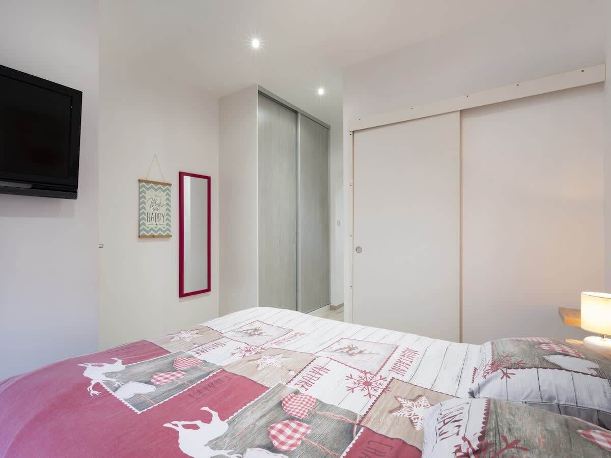 Une chambre à coucher avec un lit, une télévision, une armoire et un miroir.