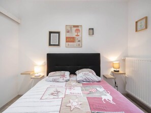 Ein Schlafzimmer mit einem Bett, zwei Nachttischen mit Lampen, einer Kopfteil und gerahmten Bildern an der Wand.