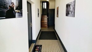 Um corredor com piso estampado, um tapete de boas-vindas e quadros nas paredes.