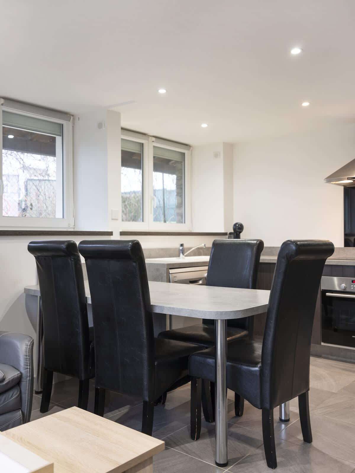 A modern kitchen with a dining area, including a table and chairs, and a built-in oven.