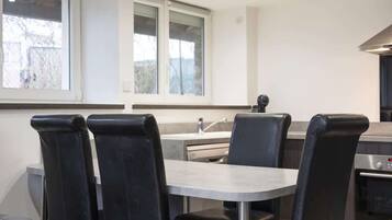 A modern kitchen with a dining area, including a table and chairs, and a built-in oven.