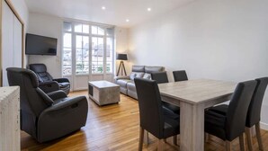 Un salon moderne avec un canapé, une table à manger et un téléviseur fixé au mur.