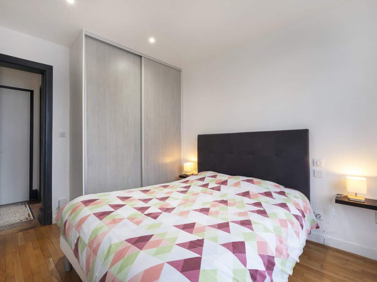 Une chambre à coucher comprenant un lit, une armoire, une table de chevet et une étagère fixée au mur.