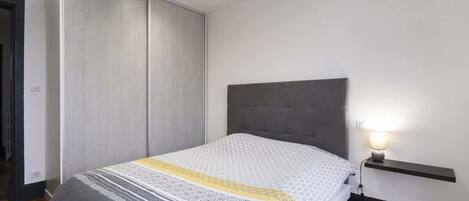 A bedroom with a bed, a bedside table with a lamp, a wardrobe, and a door.