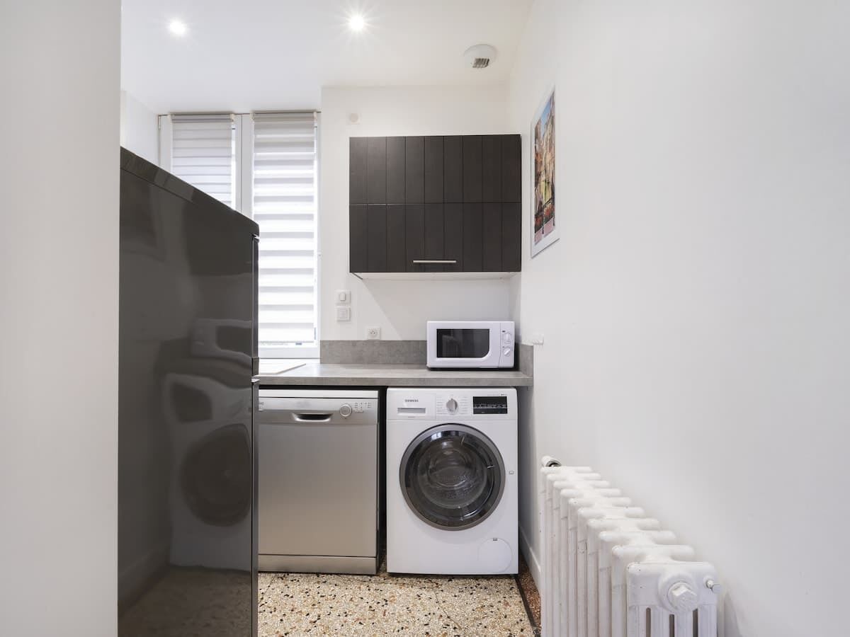 Une petite buanderie équipée d’un lave-linge, d’un sèche-linge et d’un four à micro-ondes.