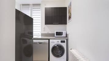 Une petite buanderie équipée d’un lave-linge, d’un sèche-linge et d’un four à micro-ondes.