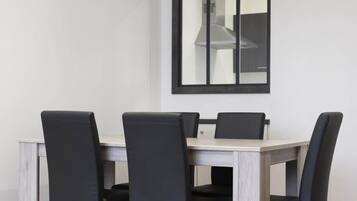 Un comedor con una mesa, sillas, un ventanal y vista a la cocina.