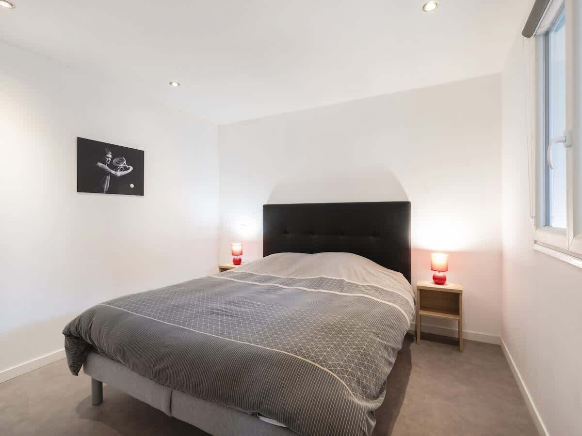 Ein Schlafzimmer mit einem Bett, zwei Nachttischen mit Lampen, einem Wandbild und einem Fenster.