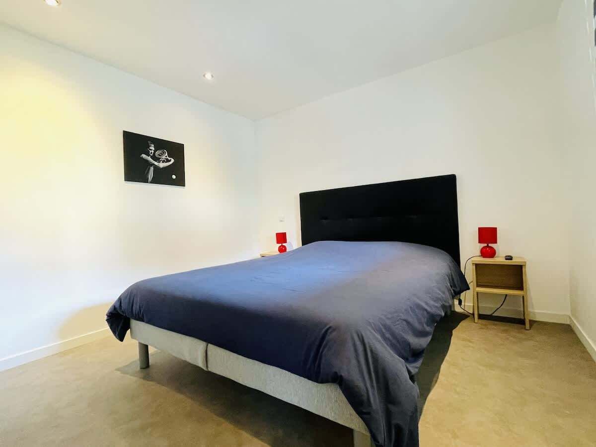 Ein Schlafzimmer mit Bett, Nachttisch und einem an der Wand hängenden Bild.
