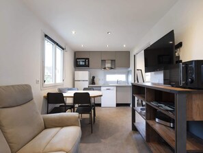 A compact living space with a kitchenette, a dining area, and a seating area. - Chalet de Romy (Vittel)