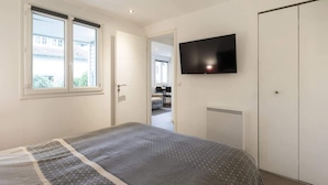 A bedroom with a bed, a TV, a wardrobe, and a window. - Chalet de Romy (Vittel)