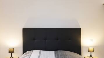 A bed with a dark headboard, two bedside lamps, and a patterned bedspread.