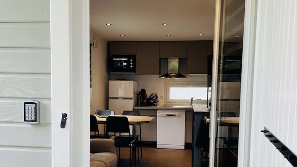 A compact kitchen with a microwave, refrigerator, and a small dining area with a table and chairs. - Chalet de Romy (Vittel)
